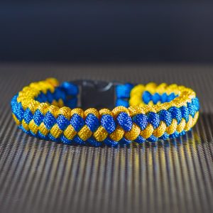 Kék és sárga paracord kötélből készült karkötő fekete műanyag csattal.