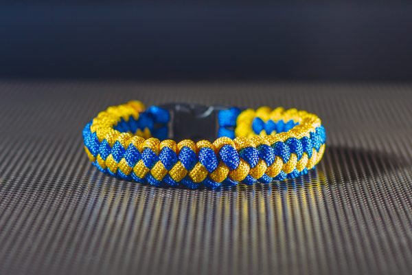 Kék és sárga paracord kötélből készült karkötő fekete műanyag csattal.