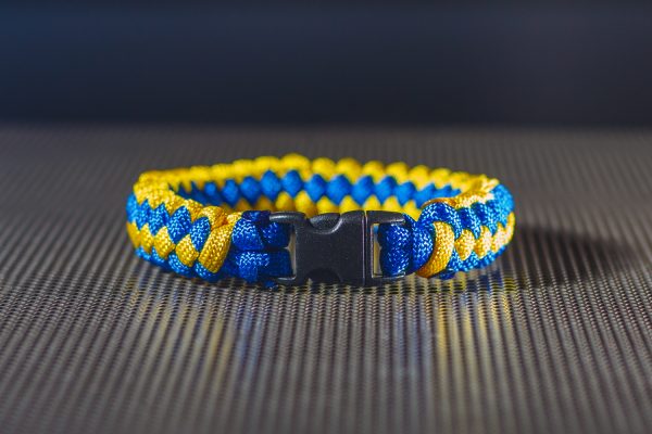 Kék és sárga paracord kötélből készült karkötő fekete műanyag csattal.